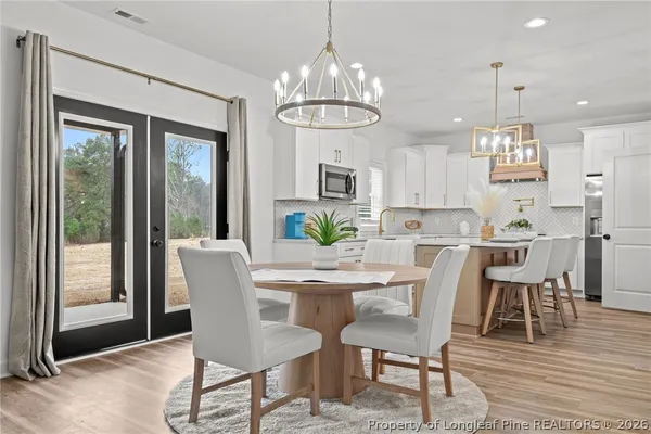 a view of a dining room with furniture a chandelier and wooden floor