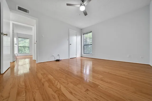 a view of empty room with wooden floor and fan