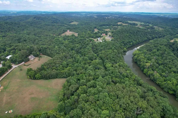 an aerial view of green landscape with trees houses and mountain view