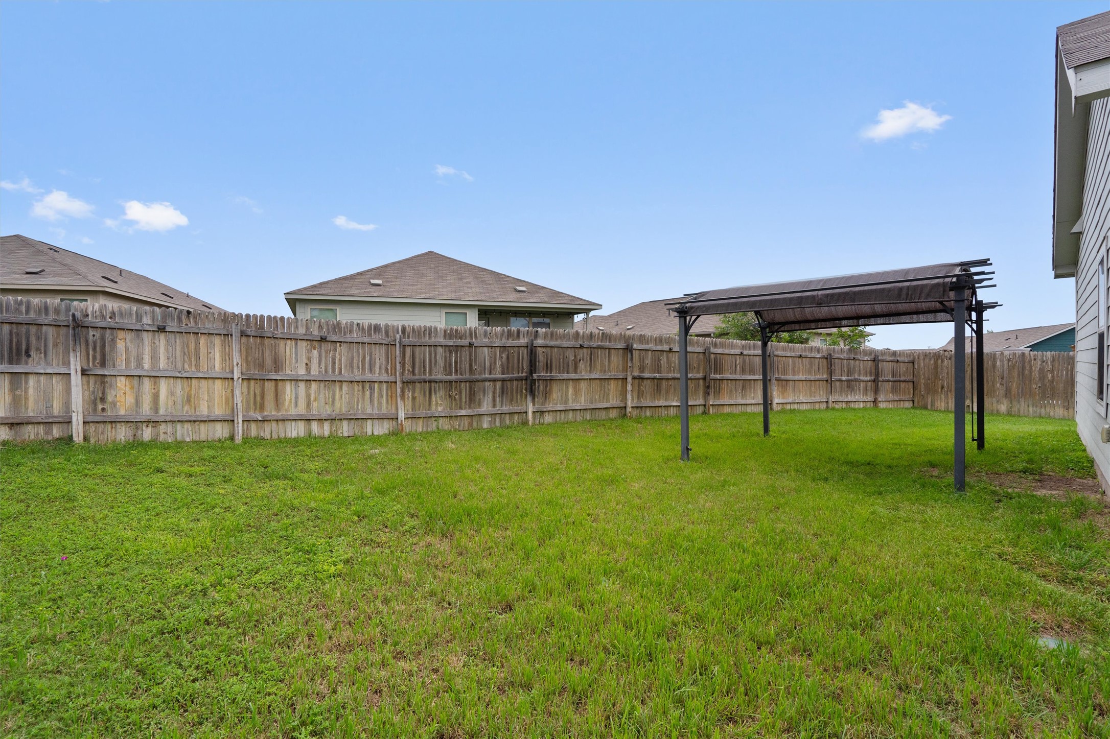 791 Circle Way Jarrell, TX 76537 - Photo 33 of 36 Expansive backyard featuring a pergola, wood privacy fencing, and a grassy lawn