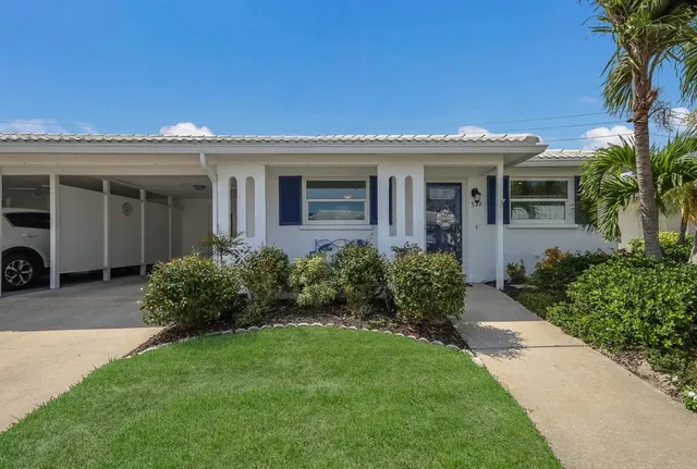 a view of a house with potted plants and a large tree