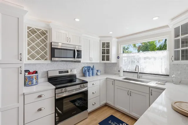 a kitchen with granite countertop a sink cabinets stainless steel appliances and a window