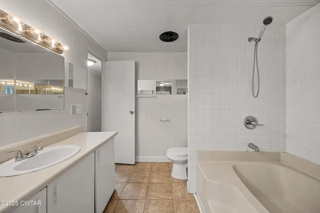 a bathroom with a bathtub shower sink mirror and toilet