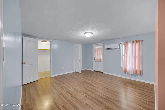 a view of an empty room with wooden floor and window