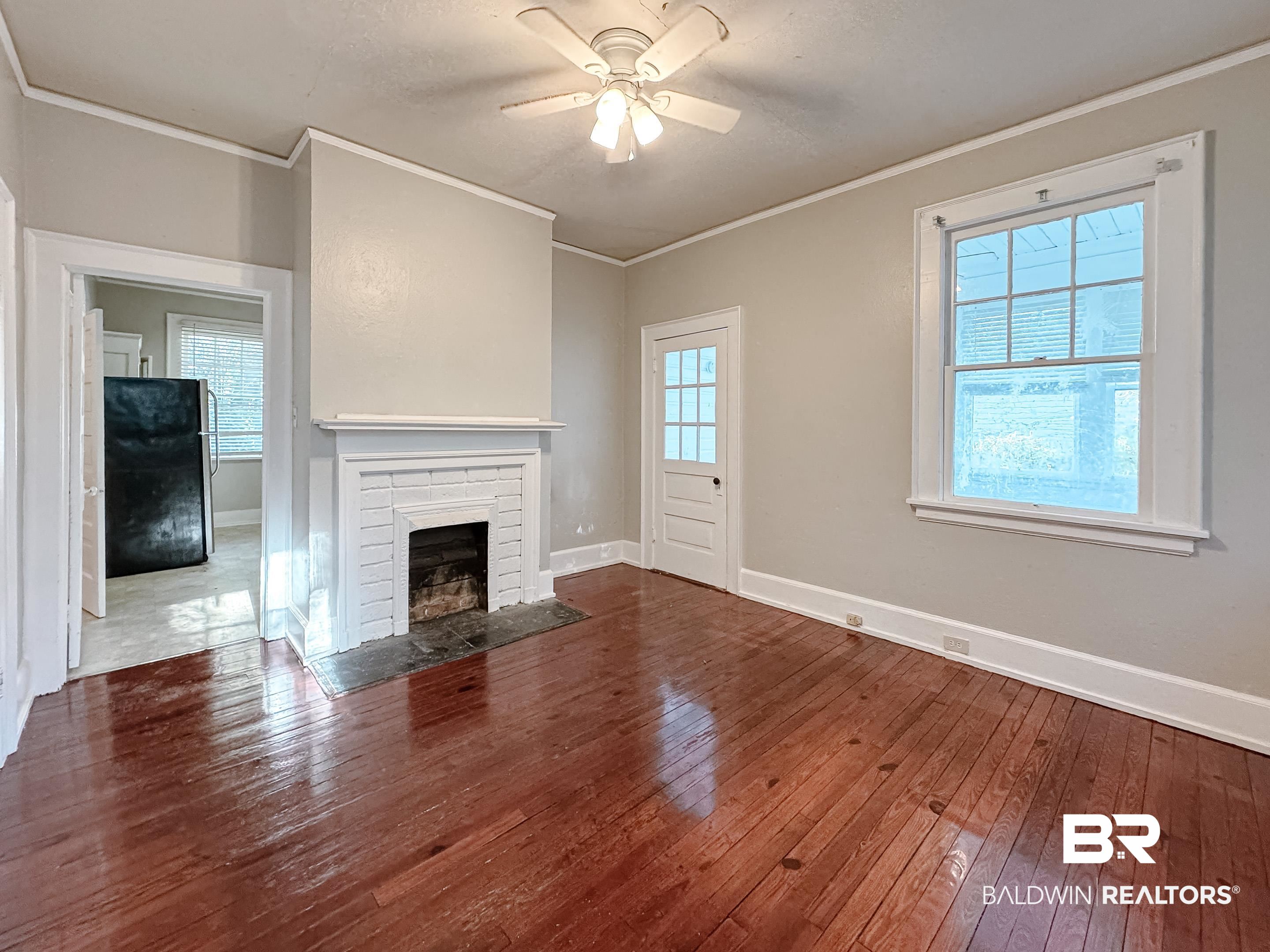 206 1st Street Mobile, AL 36611 - Photo 14 of 26 Unfurnished living room featuring crown molding, a fireplace with flush hearth, dark wood-style floors, a ceiling fan, and a textured ceiling