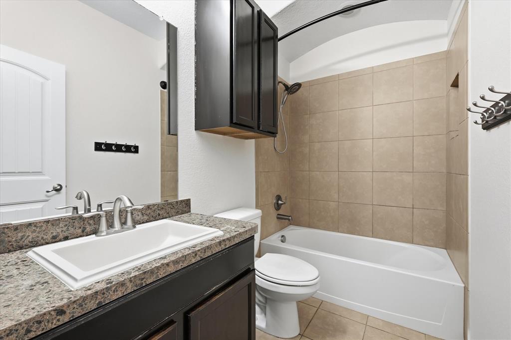 720 Rio Bravo Drive Fort Worth, TX 76052 - Photo 31 of 38 Bathroom featuring a built-in tub with tile surround, a dark wood-finish vanity with an integrated sink, and an overhead medicine cabinet