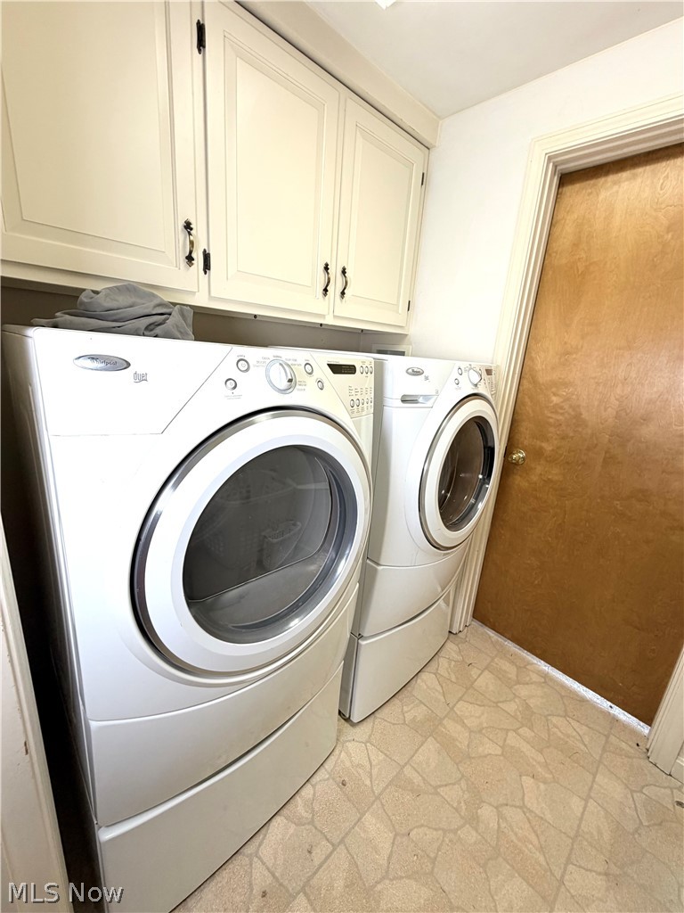 12590 Rockhaven Road Chesterland, OH 44026 - Photo 15 of 25 Laundry area featuring upper cabinetry with dark hardware, a light-colored wood door with white trim, and patterned floor tiling