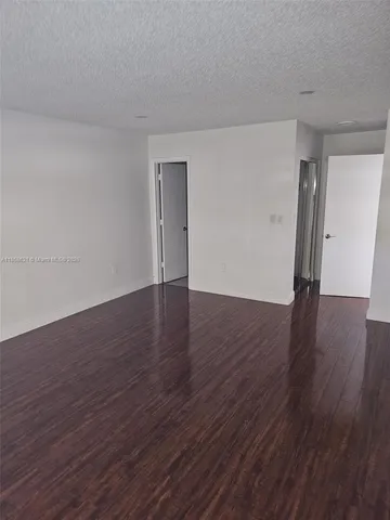 a view of an empty room with wooden floor and closet