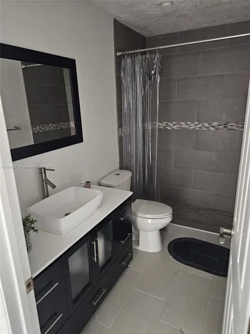 a bathroom with a granite countertop sink toilet a mirror and shower