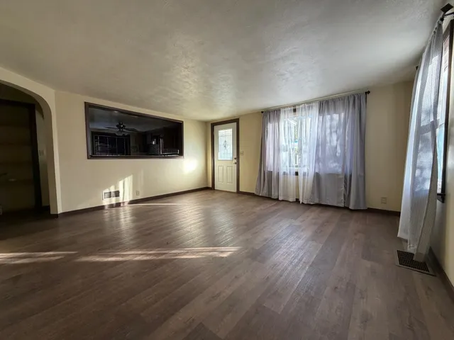an empty room with wooden floor and windows
