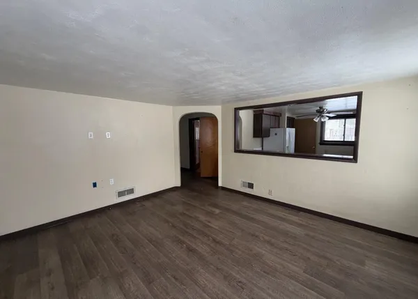 a view of a big room with wooden floor and windows