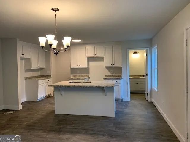 a kitchen with granite countertop a sink a stove and cabinets