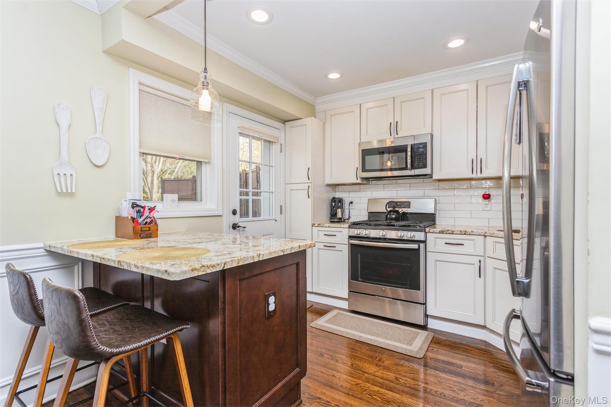 35 Peck Avenue, Unit 35A Rye, NY 10580 - Photo 4 of 27 Kitchen with appliances with stainless steel finishes, a kitchen breakfast bar, decorative light fixtures, backsplash, and light stone countertops