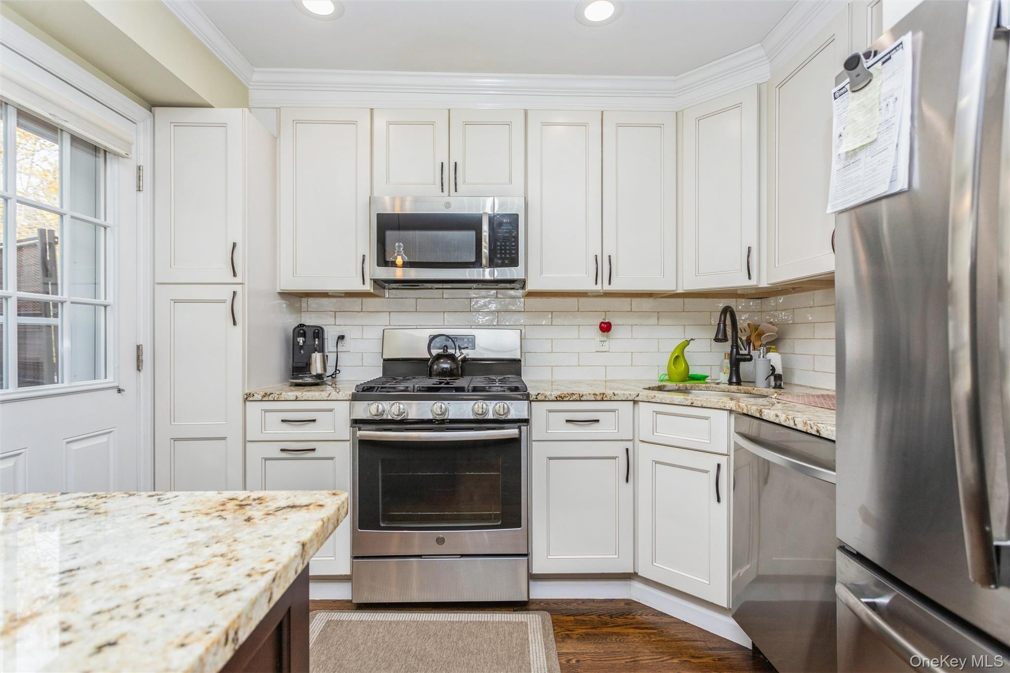 35 Peck Avenue, Unit 35A Rye, NY 10580 - Photo 6 of 27 Kitchen with appliances with stainless steel finishes, light stone counters, white cabinets, decorative backsplash, and dark wood-type flooring