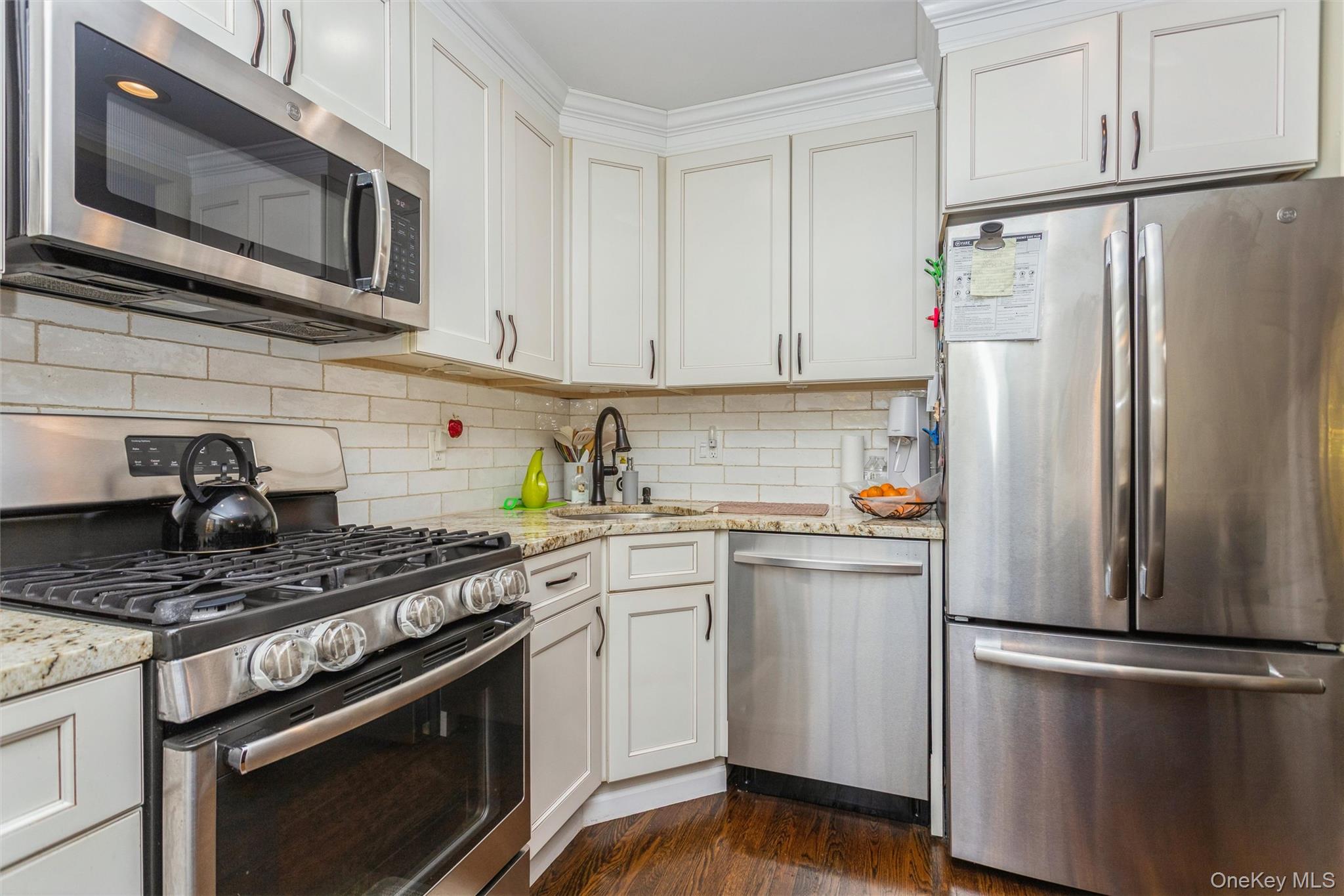 35 Peck Avenue, Unit 35A Rye, NY 10580 - Photo 7 of 27 Kitchen with appliances with stainless steel finishes, light stone counters, white cabinets, dark wood-style flooring, and decorative backsplash
