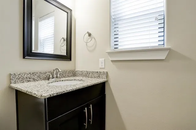 a bathroom with a granite countertop sink and a mirror