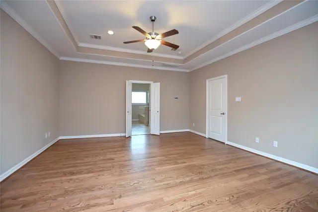 a view of an empty room with chandelier fan and wooden floor