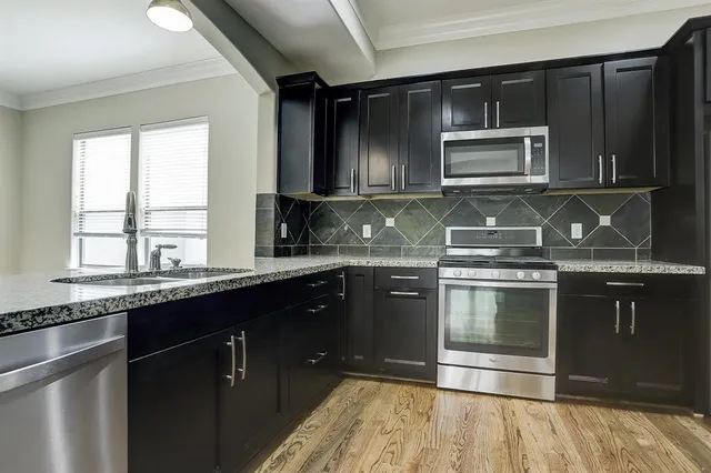 a kitchen with granite countertop a sink stove and microwave