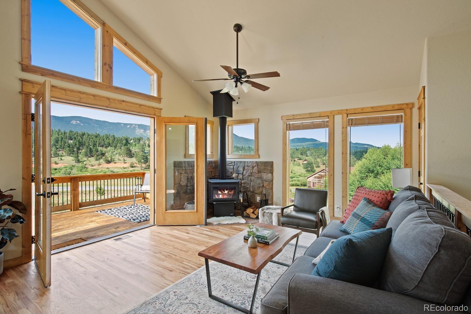 1328 Clark Road Bailey, CO 80421 - Photo 13 of 37 a living room with furniture a ceiling fan and a floor to ceiling window