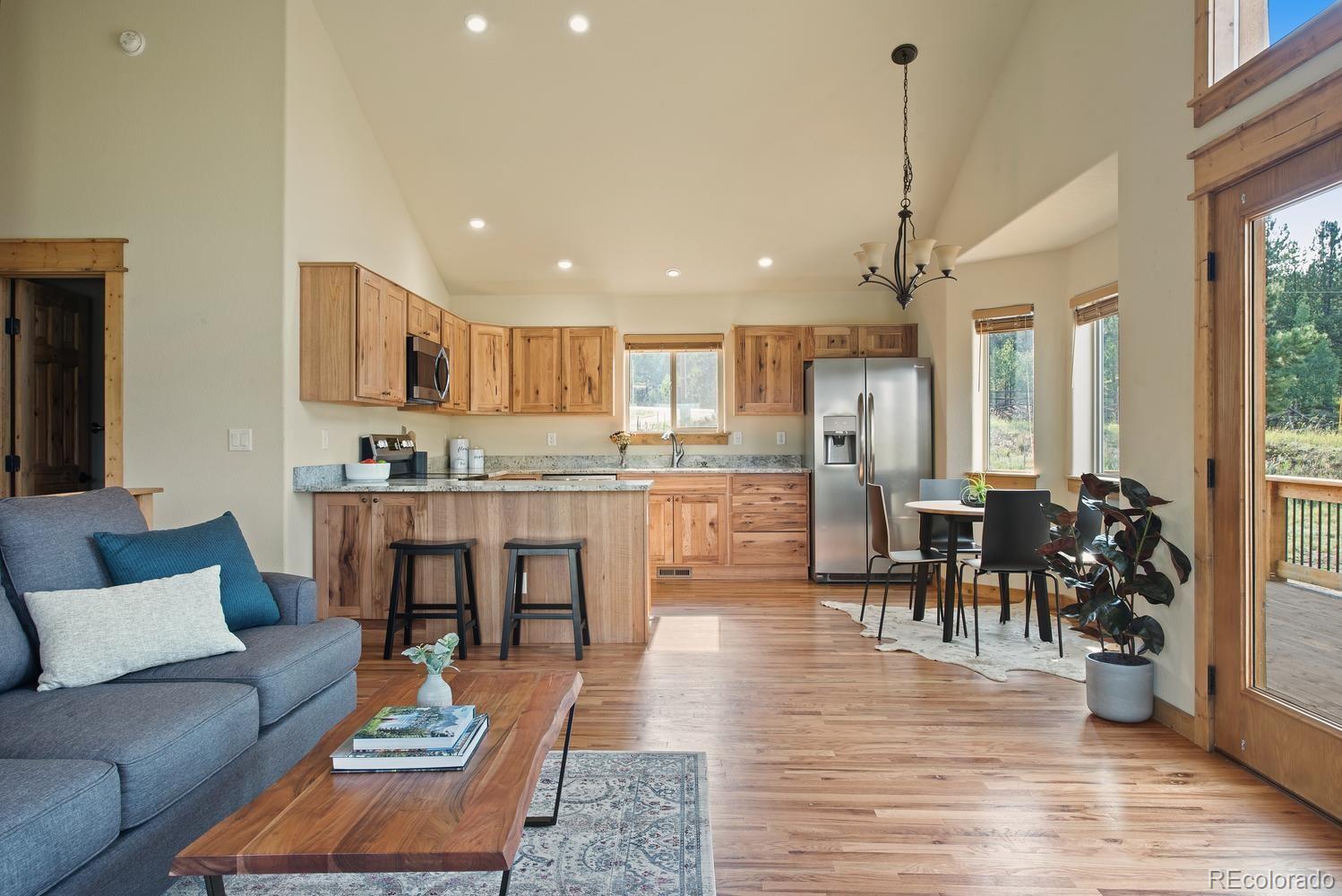1328 Clark Road Bailey, CO 80421 - Photo 18 of 37 a living room with stainless steel appliances kitchen island granite countertop furniture and a wooden floor