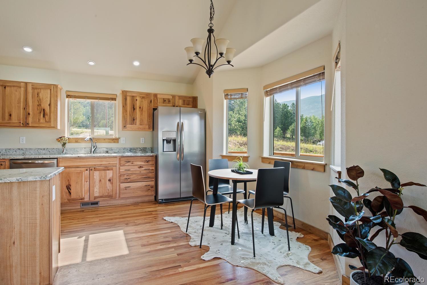 1328 Clark Road Bailey, CO 80421 - Photo 20 of 37 a kitchen with stainless steel appliances granite countertop a stove a refrigerator and a dining table with wooden floor