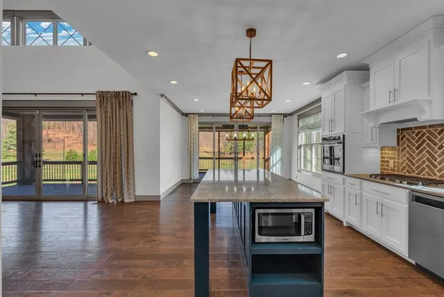 a kitchen with kitchen island granite countertop a stove and a wooden floors