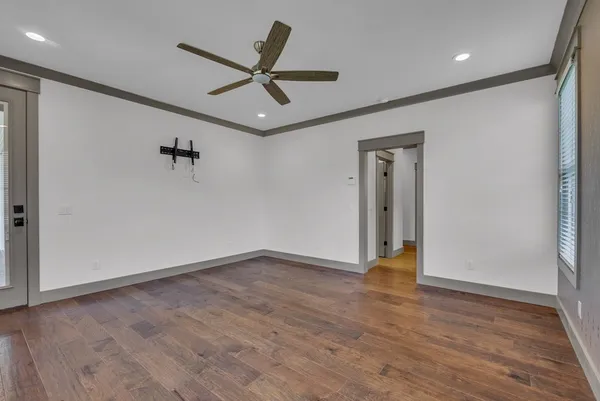 an empty room with wooden floor and a ceiling fan