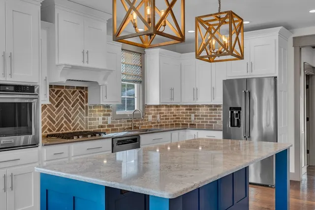 a kitchen with stainless steel appliances granite countertop a sink a microwave a stove and refrigerator