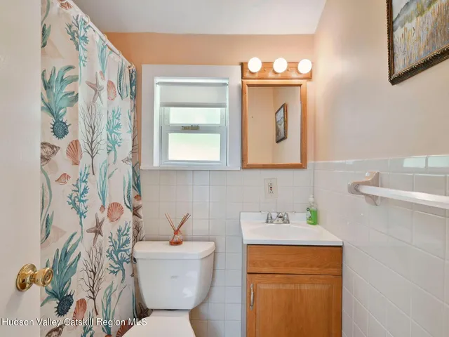 a bathroom with a sink a mirror a toilet and a window