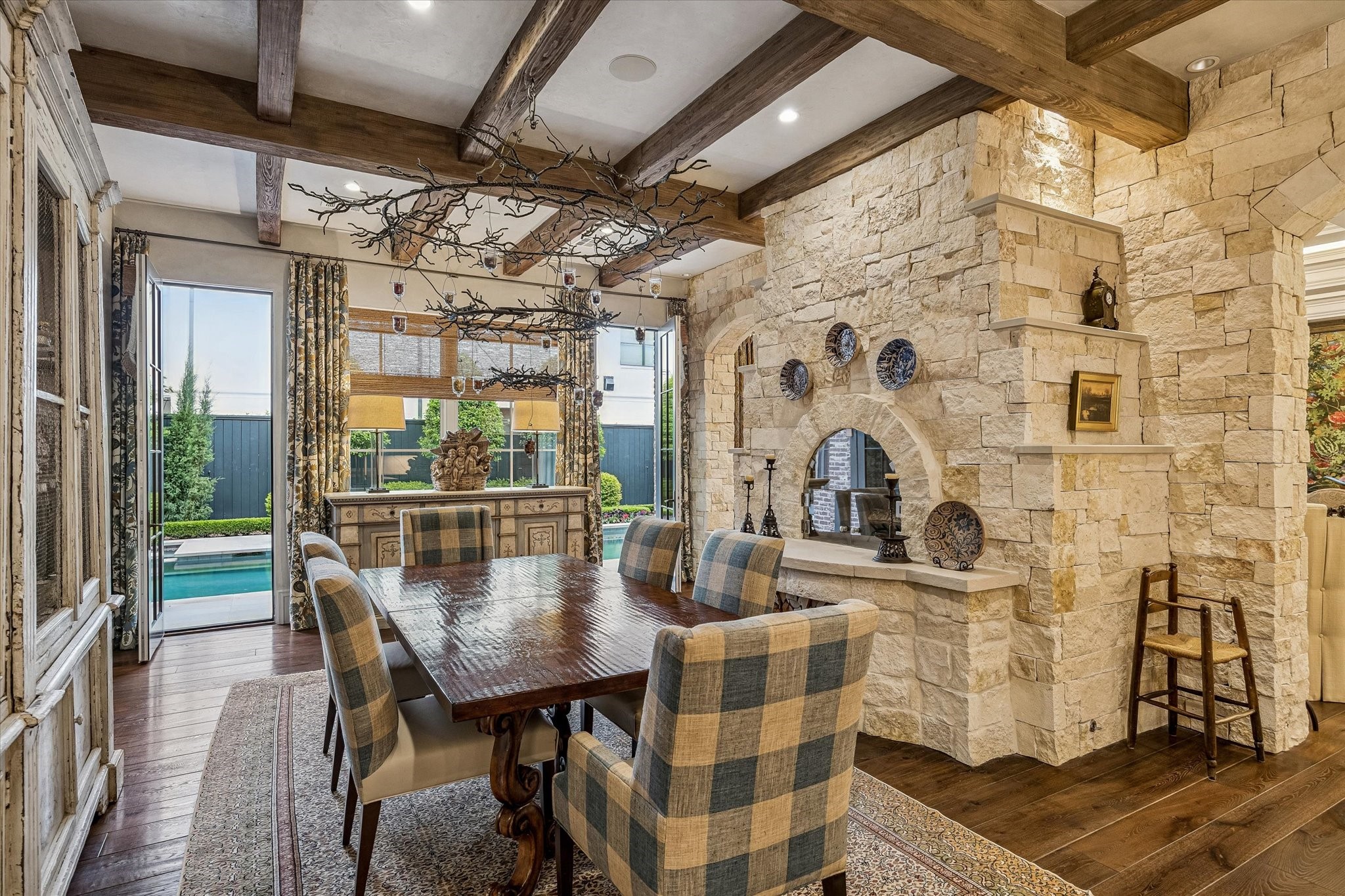2158 Chilton Road Houston, TX 77019 - Photo 17 of 50 The breakfast room is a sunlit retreat with tranquil backyard views, highlighted by a beamed and Segreto plaster ceiling. A limestone-surround pizza oven/fireplace adds warmth and charm to this inviting space.