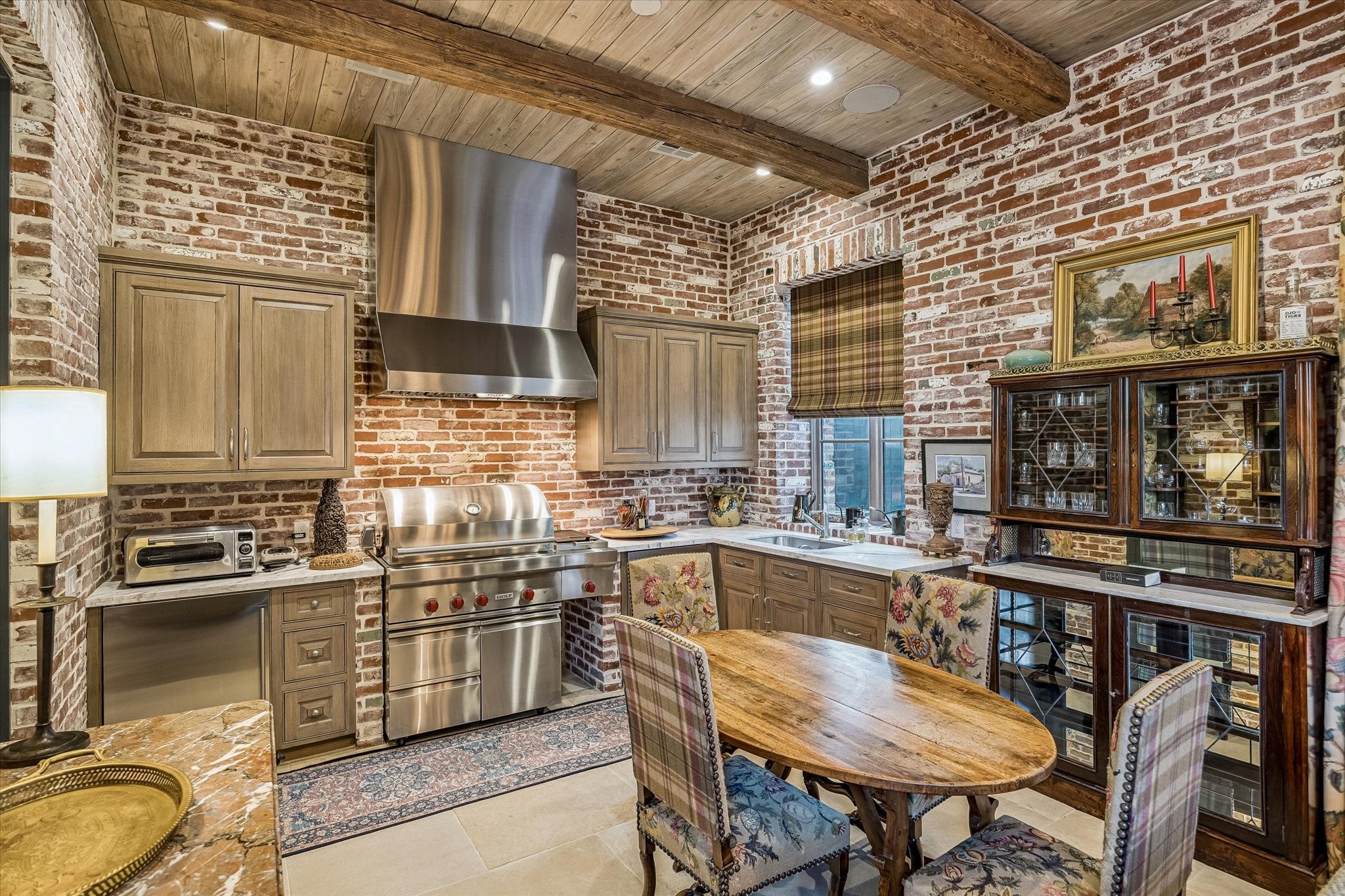 2158 Chilton Road Houston, TX 77019 - Photo 26 of 50 Perfect for entertaining in any season, this stunning sunroom offers a built-in grill, beverage refrigeration, and motorized shades for effortless comfort. Warm brick accents and a reclaimed wood mantle create an inviting, relaxed atmosphere.