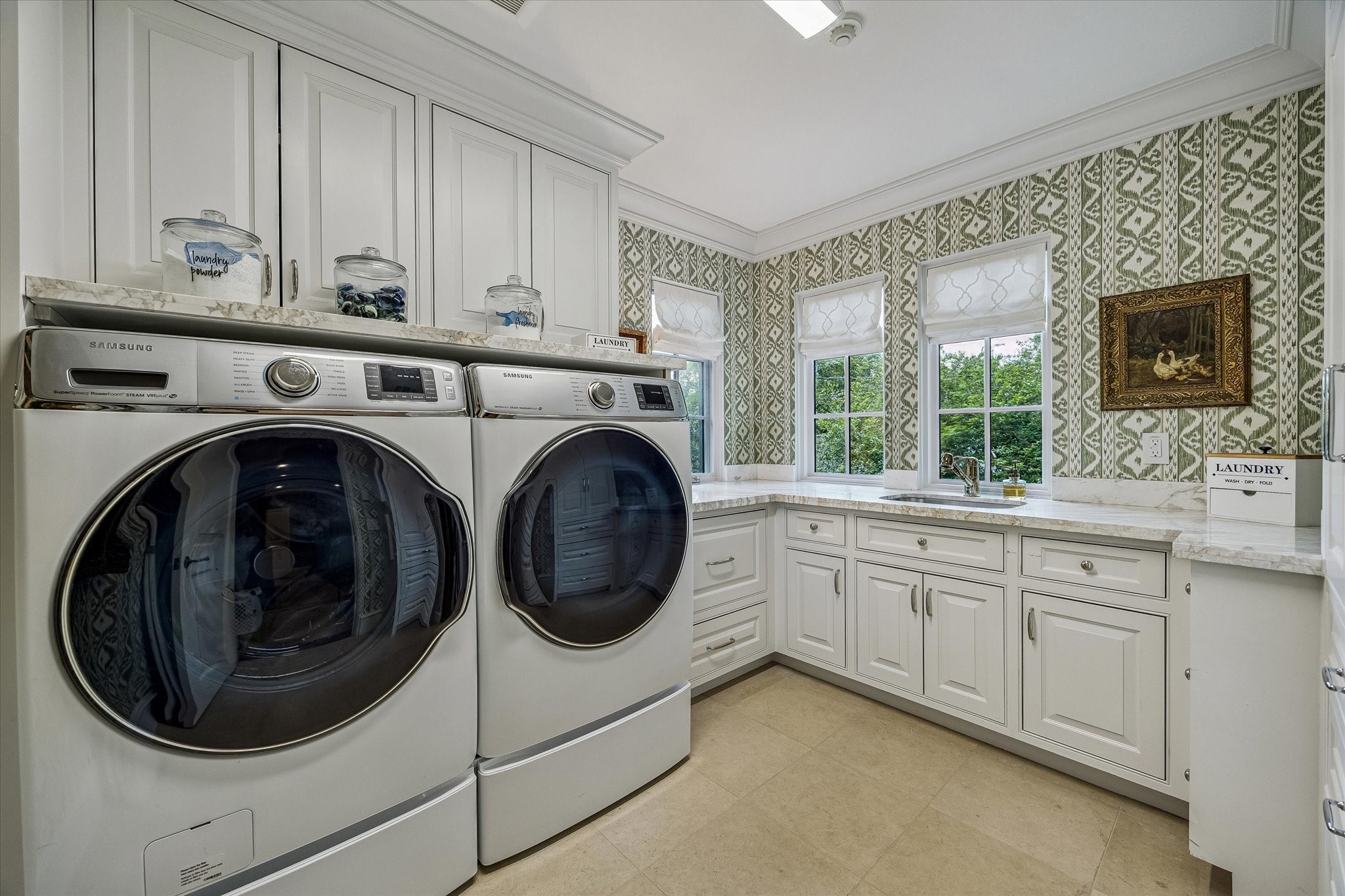 2158 Chilton Road Houston, TX 77019 - Photo 43 of 50 The utility room combines style and function with tile flooring, marble countertops, stainless steel sink, and Samsung washer and dryer. Green Rapallo wallpaper and ample storage make this space both practical and inviting.
