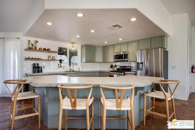 a kitchen with stainless steel appliances granite countertop a stove top oven a sink a dining table and chairs with wooden floor