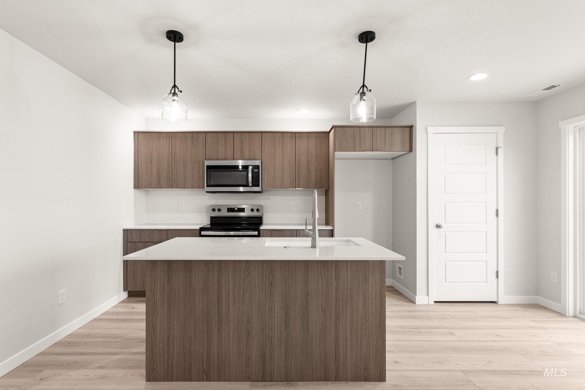 10830 Rutland Street Caldwell, ID 83605 - Photo 3 of 21 Kitchen featuring pendant lighting, stainless steel appliances, light wood-style flooring, and modern cabinets