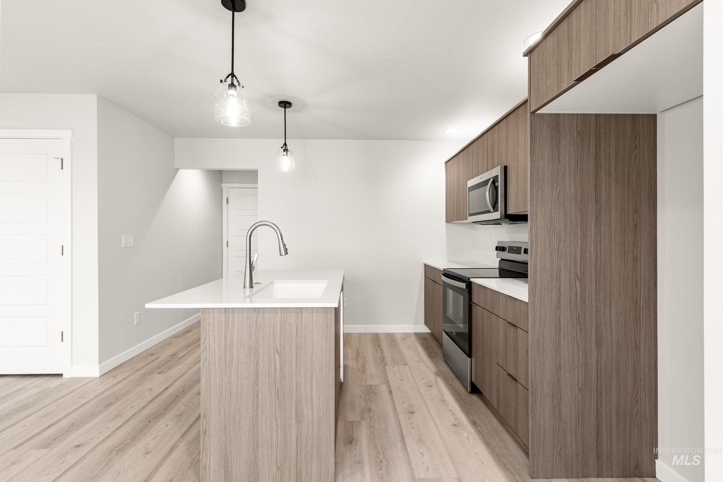 10830 Rutland Street Caldwell, ID 83605 - Photo 7 of 21 Kitchen featuring stainless steel appliances, modern cabinets, an island with sink, and hanging light fixtures