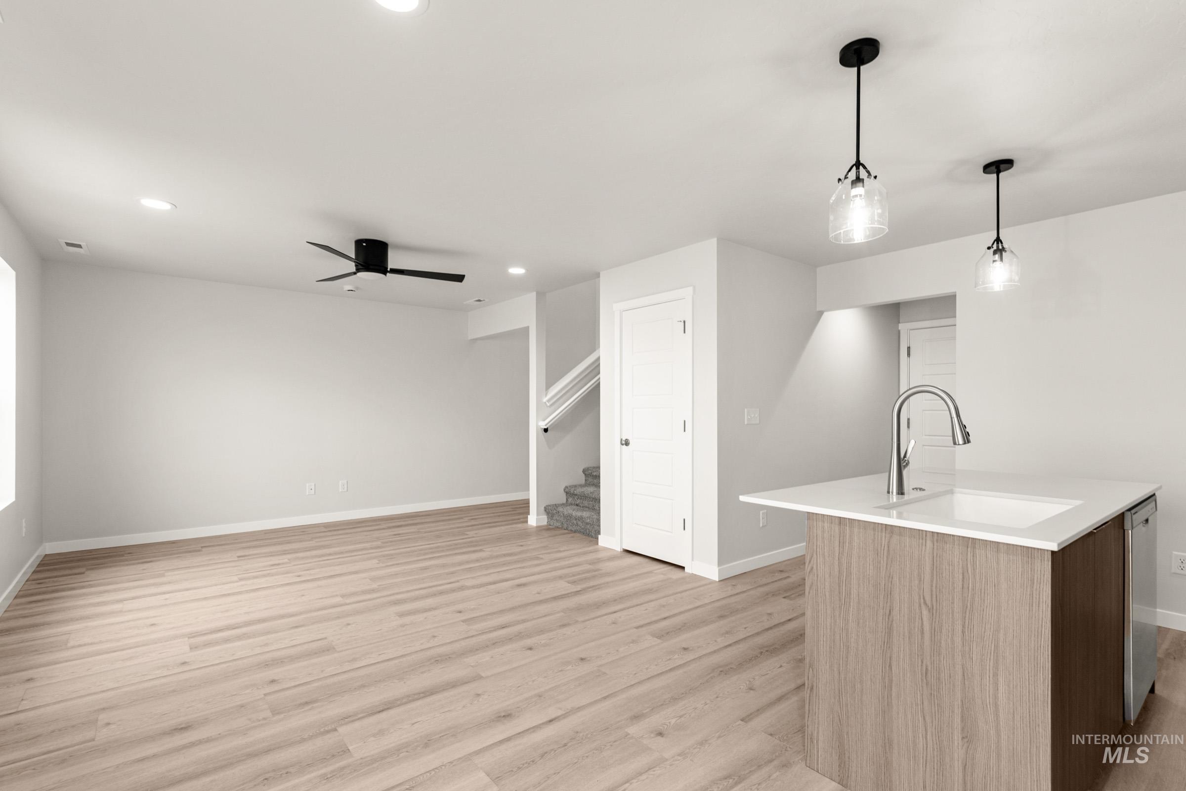 10830 Rutland Street Caldwell, ID 83605 - Photo 8 of 21 Kitchen with a kitchen island with sink, decorative light fixtures, light wood-style flooring, a ceiling fan, and stainless steel dishwasher