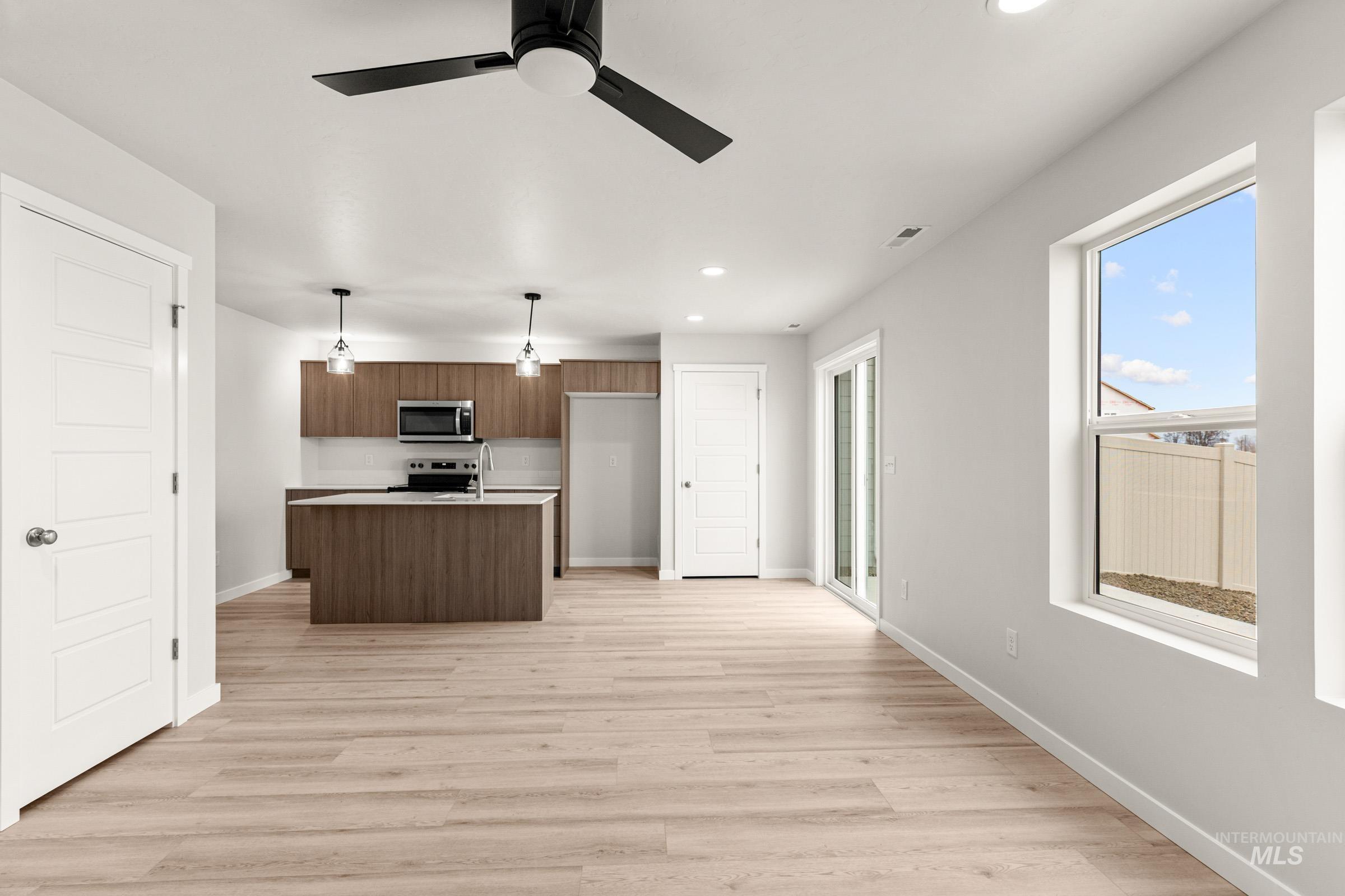 10830 Rutland Street Caldwell, ID 83605 - Photo 10 of 21 Kitchen featuring light countertops, a center island with sink, pendant lighting, light wood-type flooring, and stainless steel appliances