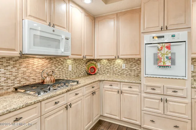 a view of a swimming pool with lawn chairs and large trees