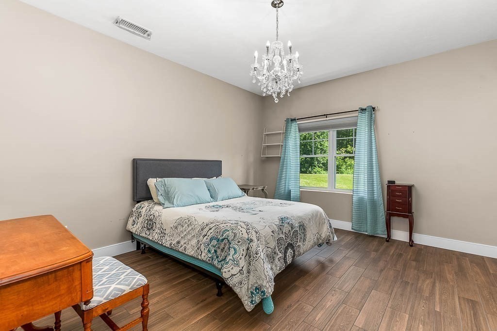 196 Glenwood Road Rutland, MA 01543 - Photo 25 of 37 a bedroom with a large bed and a chandelier