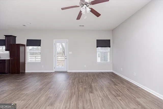 a large white kitchen with kitchen island a sink wooden floor and stainless steel appliances