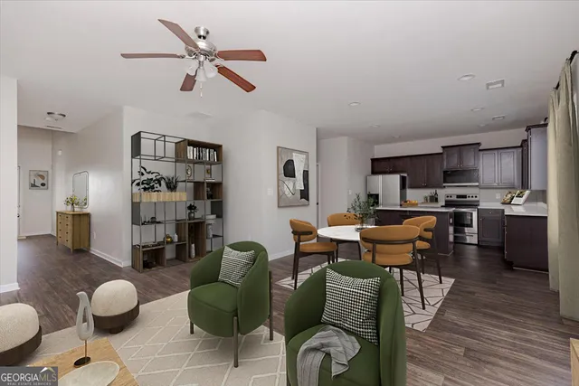 a living room with furniture kitchen view and a wooden floor
