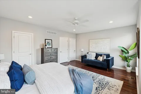 a spacious bedroom with a bed a couch and wooden floor