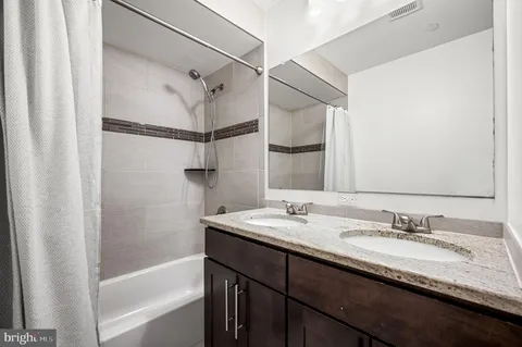 a bathroom with a granite countertop sink mirror and a bath tub