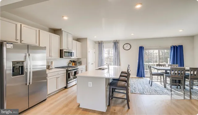 a large kitchen with stainless steel appliances lots of white cabinets a dining table and chairs