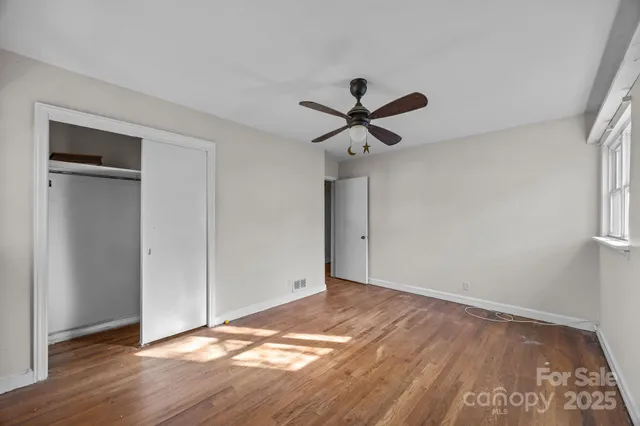 an empty room with wooden floor and ceiling fan