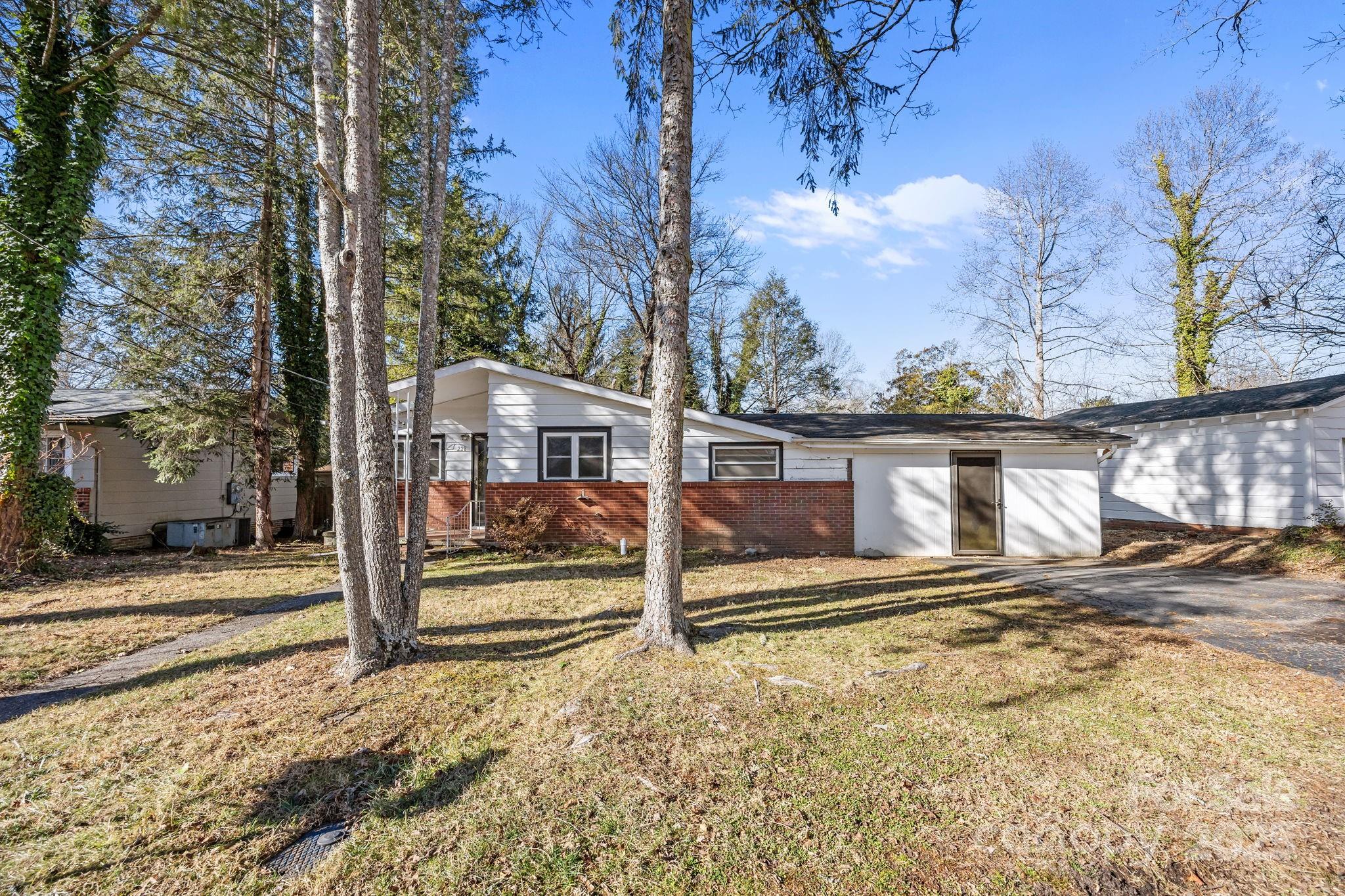 228 Grove Street Brevard, NC 28712 - Photo 4 of 44 a view of a house with a large tree and wooden fence