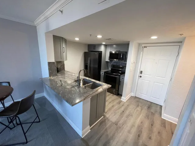 a kitchen with stainless steel appliances granite countertop a sink and a refrigerator
