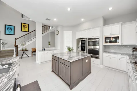 a kitchen with stainless steel appliances granite countertop a refrigerator a stove and a sink