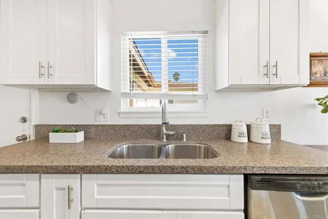 a kitchen with granite countertop a sink a window and cabinets