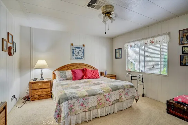 a bedroom with a bed a desk and chair with window